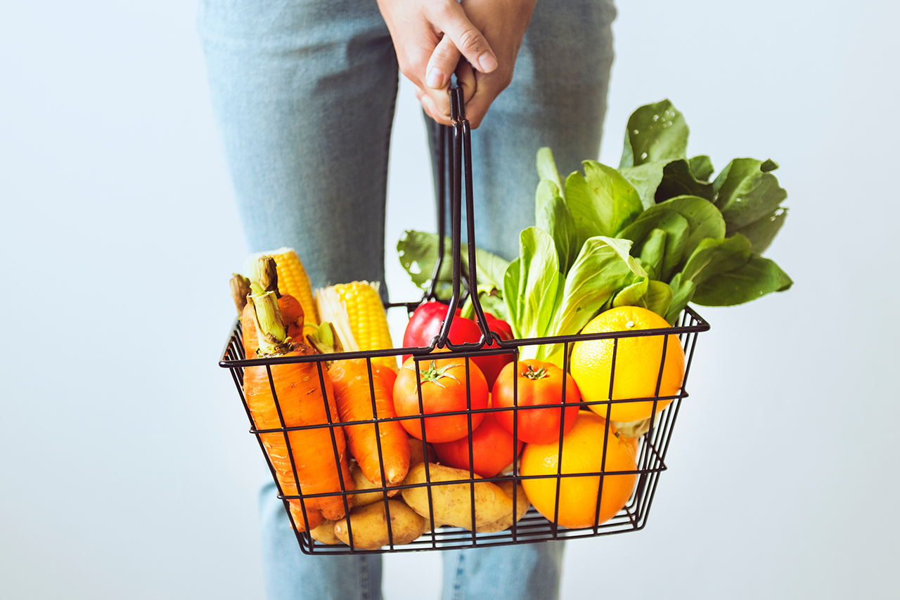 野菜や果物の籠を持った女性